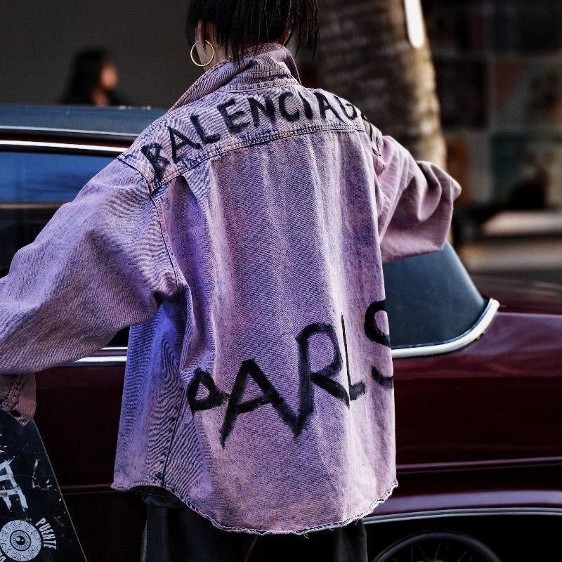 Sanhoostudio denim shirt jacket featuring Paris-inspired graffiti artwork and distressed washed finish in dusty pink tone. Designed with a loose fit and classic collar for modern vintage streetwear styling.