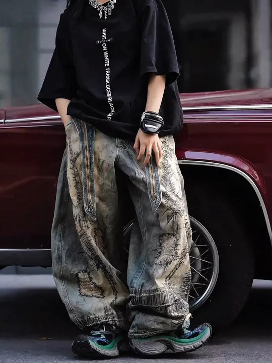 Sanhoostudio wide leg denim pants featuring distressed wash, heavy embroidery, and wasteland-inspired design. Built with a loose fit silhouette for bold streetwear styling.