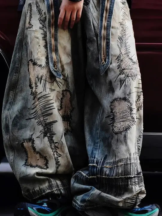 Sanhoostudio wide leg denim pants featuring distressed wash, heavy embroidery, and wasteland-inspired design. Built with a loose fit silhouette for bold streetwear styling.