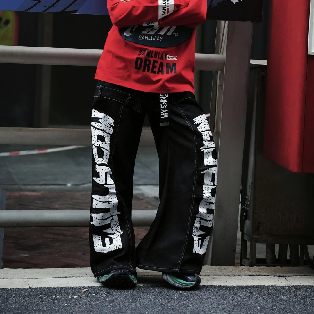 Sanhoostudio denim pants featuring scythe-cut silhouette and letter print design for modern streetwear styling.