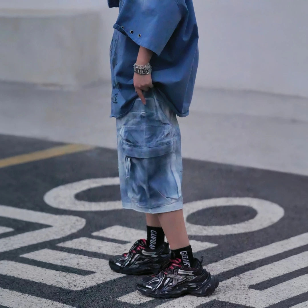 Sanhoostudio cargo shorts featuring tie dye finish, multi-pocket design, and relaxed wide leg fit. Built for summer streetwear styling with breathable comfort, lightweight feel, and functional everyday wear.