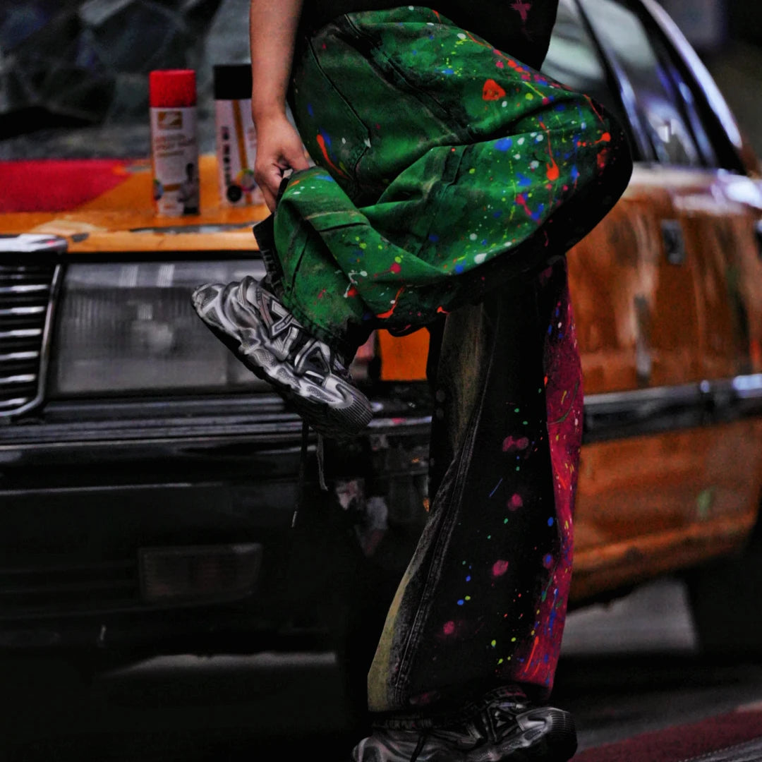 Sanhoostudio denim pants featuring graffiti artwork, patchwork construction, and distressed wash finish. Designed with a wide leg silhouette for bold streetwear styling with durability and comfort.