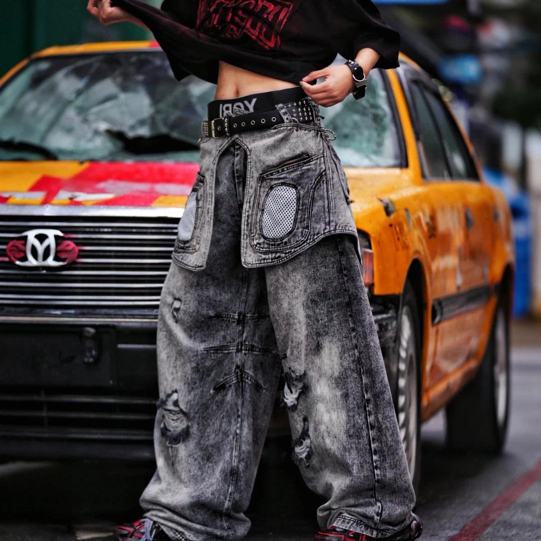 Sanhoostudio denim pants featuring layered patchwork construction, distressed wash finish, and detachable styling elements. Designed for bold streetwear outfits with relaxed comfort and unique visual structure.