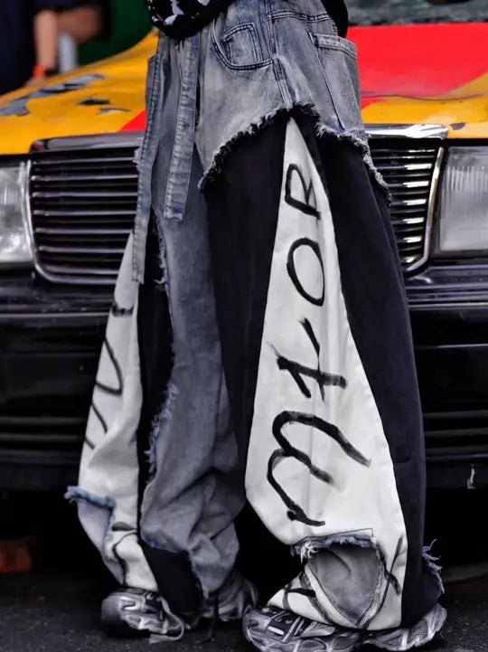 Sanhoostudio denim pants featuring distressed washed finish, patchwork detailing, and wide leg scythe-cut silhouette. Designed for modern streetwear styling with relaxed comfort and versatile everyday wear.