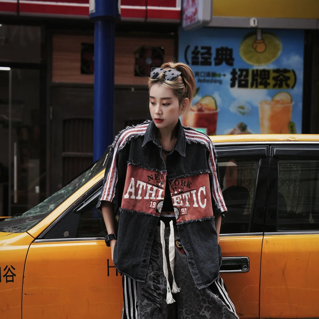 Sanhoostudio denim short sleeve shirt featuring patchwork construction, fringe detailing, and letter-inspired design elements. Built for creative streetwear outfits with a relaxed fit and standout visual appeal.
