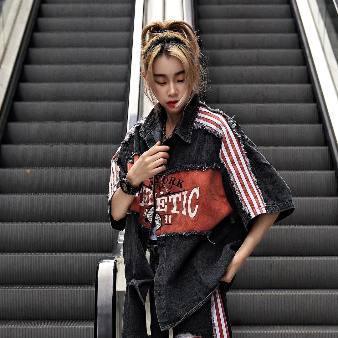 Sanhoostudio denim short sleeve shirt featuring patchwork construction, fringe detailing, and letter-inspired design elements. Built for creative streetwear outfits with a relaxed fit and standout visual appeal.
