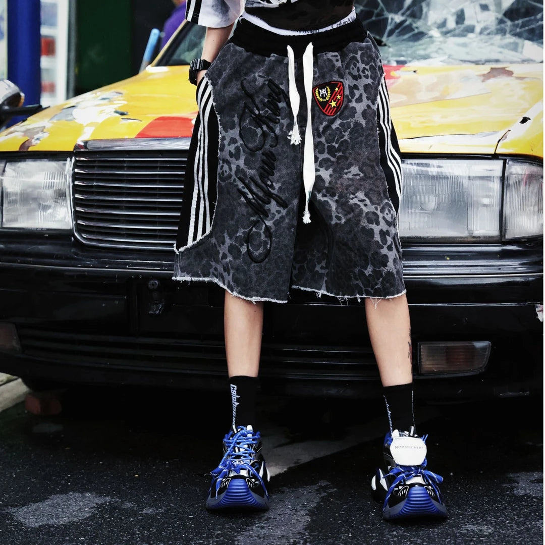Sanhoostudio shorts featuring leopard print detailing, embroidered accents, and a relaxed scythe-inspired silhouette. Designed for summer streetwear styling with comfort, mobility, and bold visual impact.