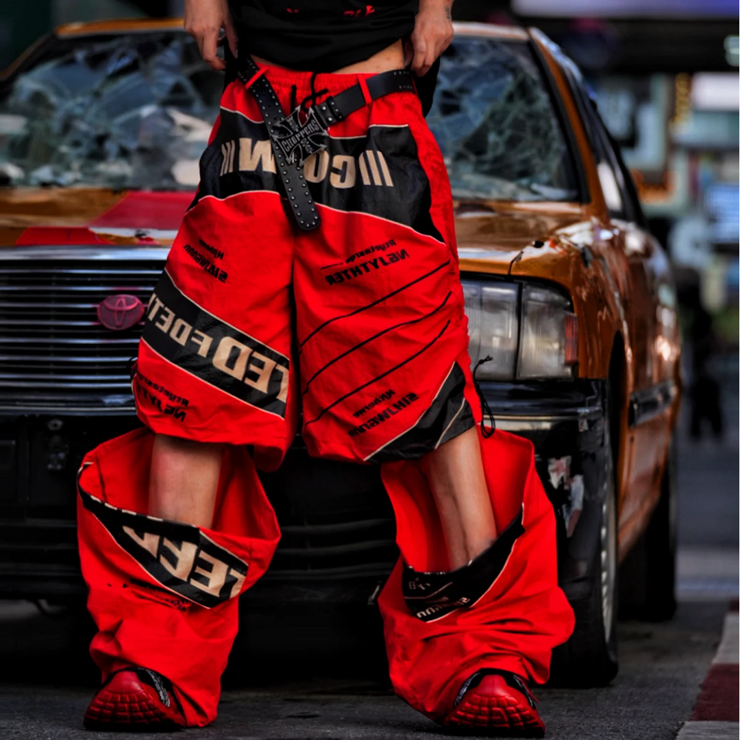 Sanhoostudio wide leg pants featuring detachable styling elements, racing-inspired panel construction, and a relaxed fit. Designed for modern streetwear outfits with comfort, versatility, and bold visual appeal.
