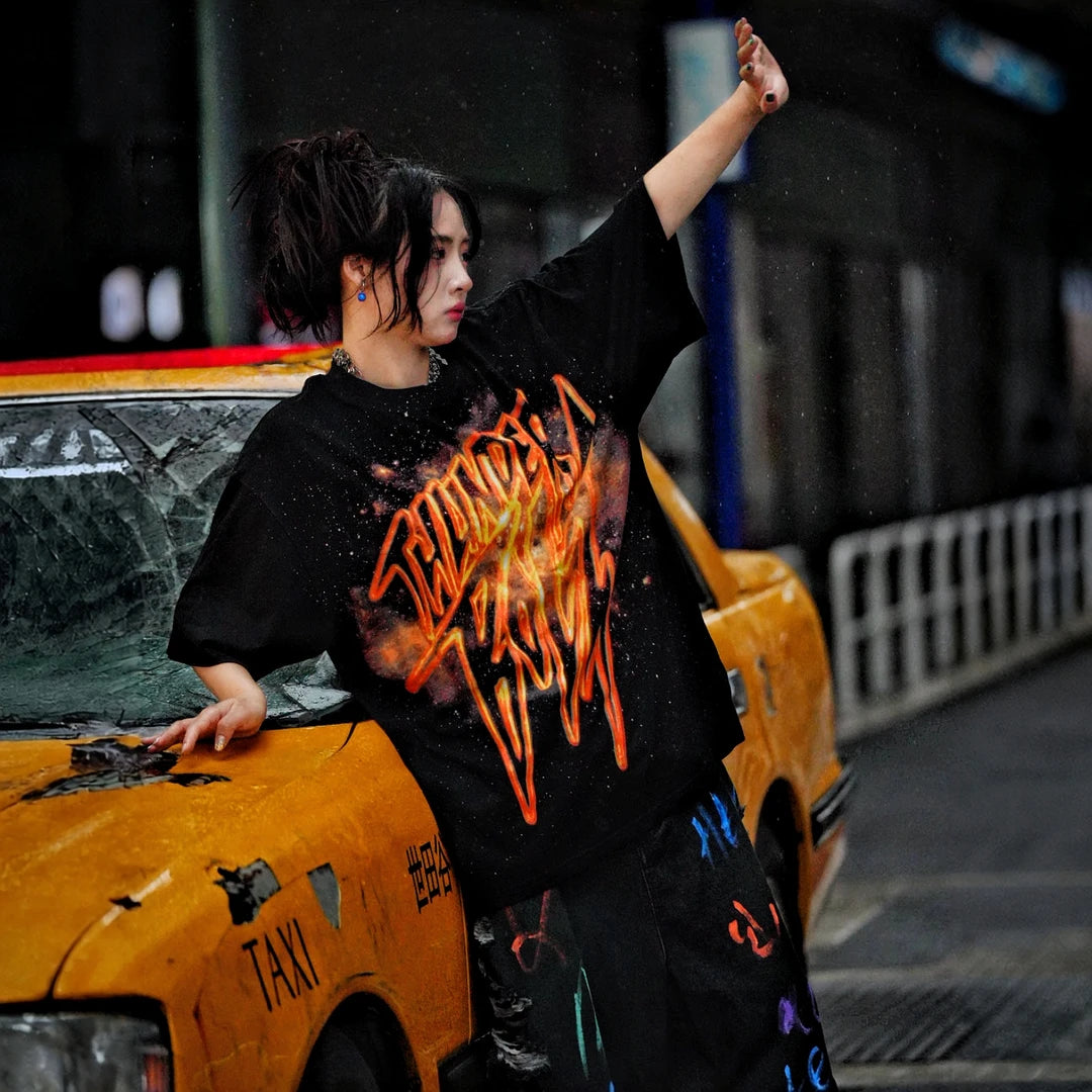 Sanhoostudio short sleeve T-shirt featuring gold-inspired spray-print graphics, breathable fabric construction, and a relaxed oversized fit. Built for standout summer streetwear outfits with comfort and unique visual expression.