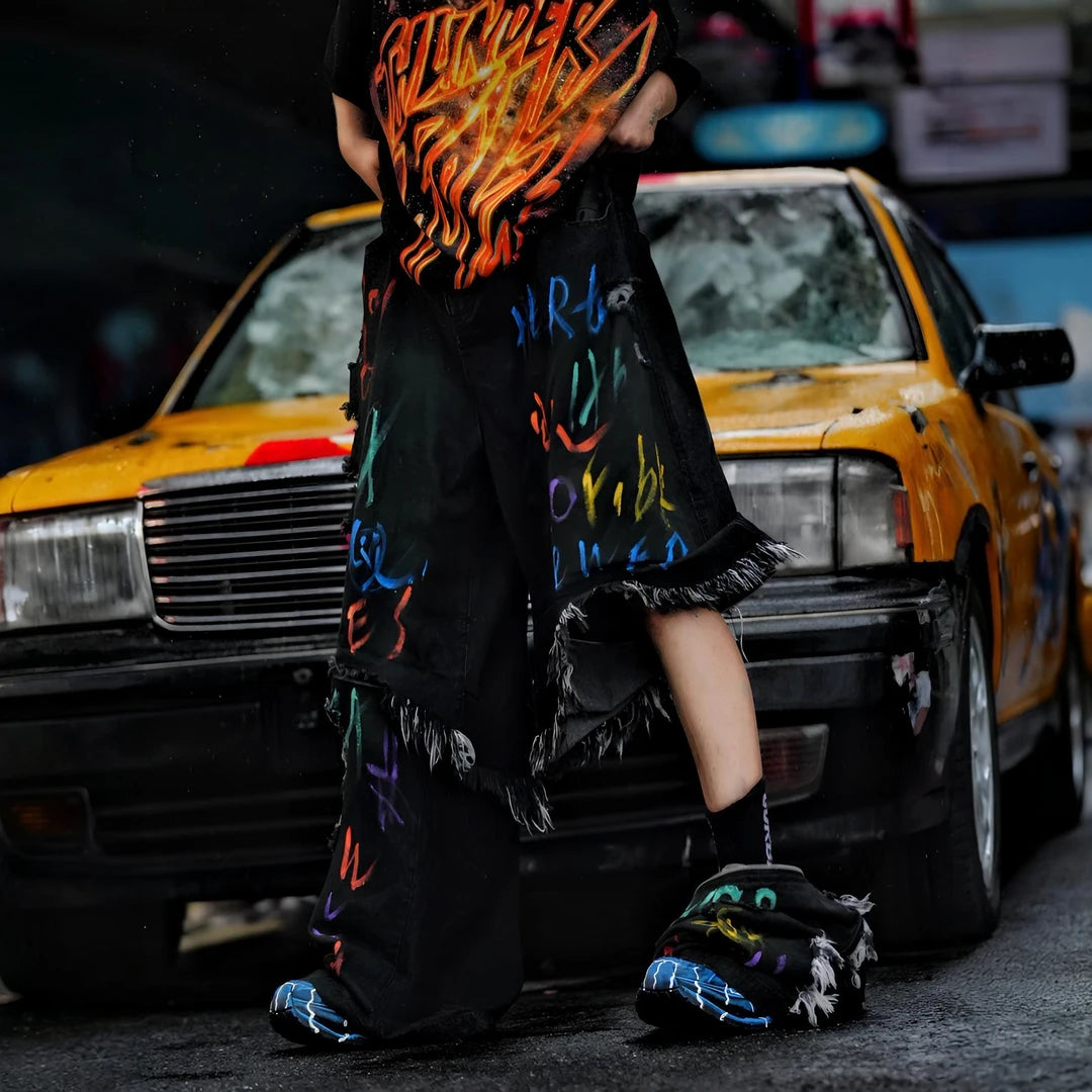Sanhoostudio convertible denim pants featuring detachable long-to-short functionality, distressed wash treatment, and a wide leg scythe-cut silhouette. Designed for versatile streetwear styling with comfort and standout visual appeal.