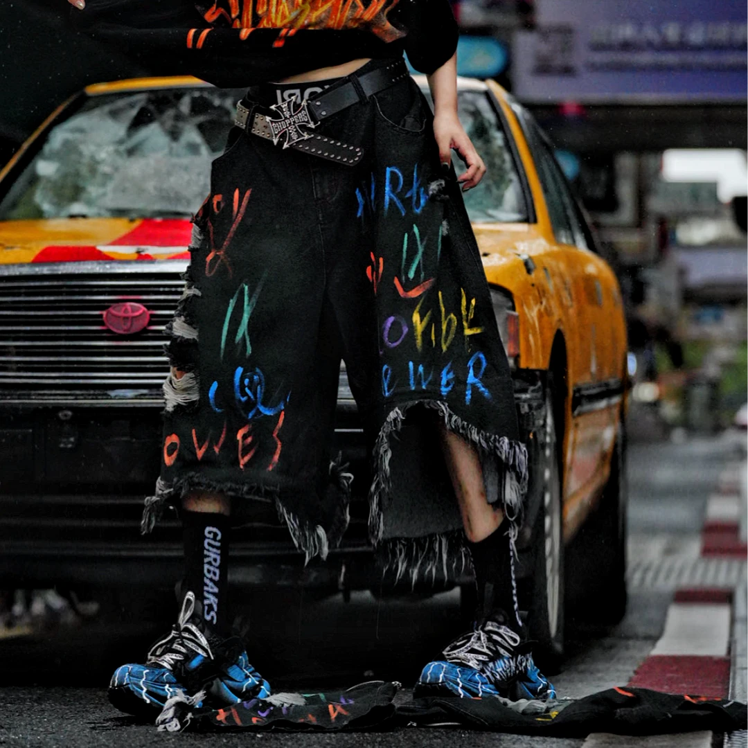 Sanhoostudio convertible denim pants featuring detachable long-to-short functionality, distressed wash treatment, and a wide leg scythe-cut silhouette. Designed for versatile streetwear styling with comfort and standout visual appeal.
