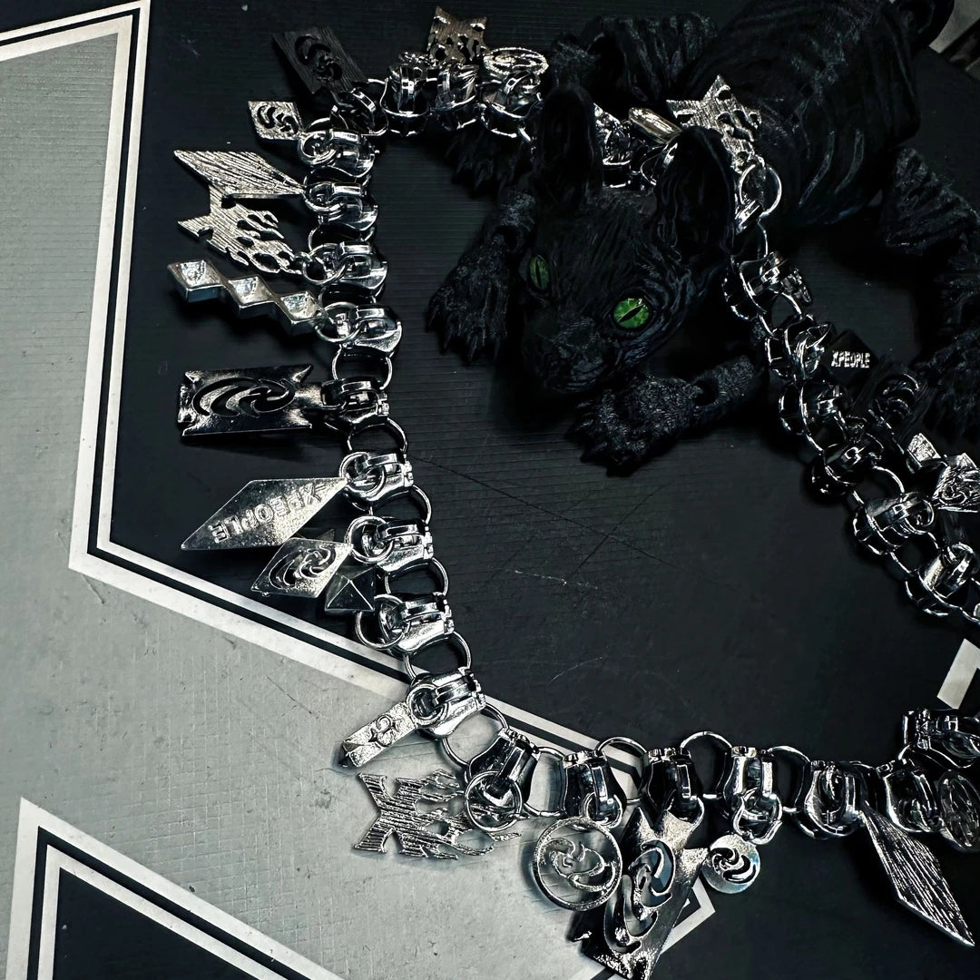 Sanhoostudio alloy necklace featuring multiple zipper-pull pendants and a heavyweight punk-inspired design. Crafted for streetwear styling with bold layering, durable construction, and a distinctive urban aesthetic for everyday wear.