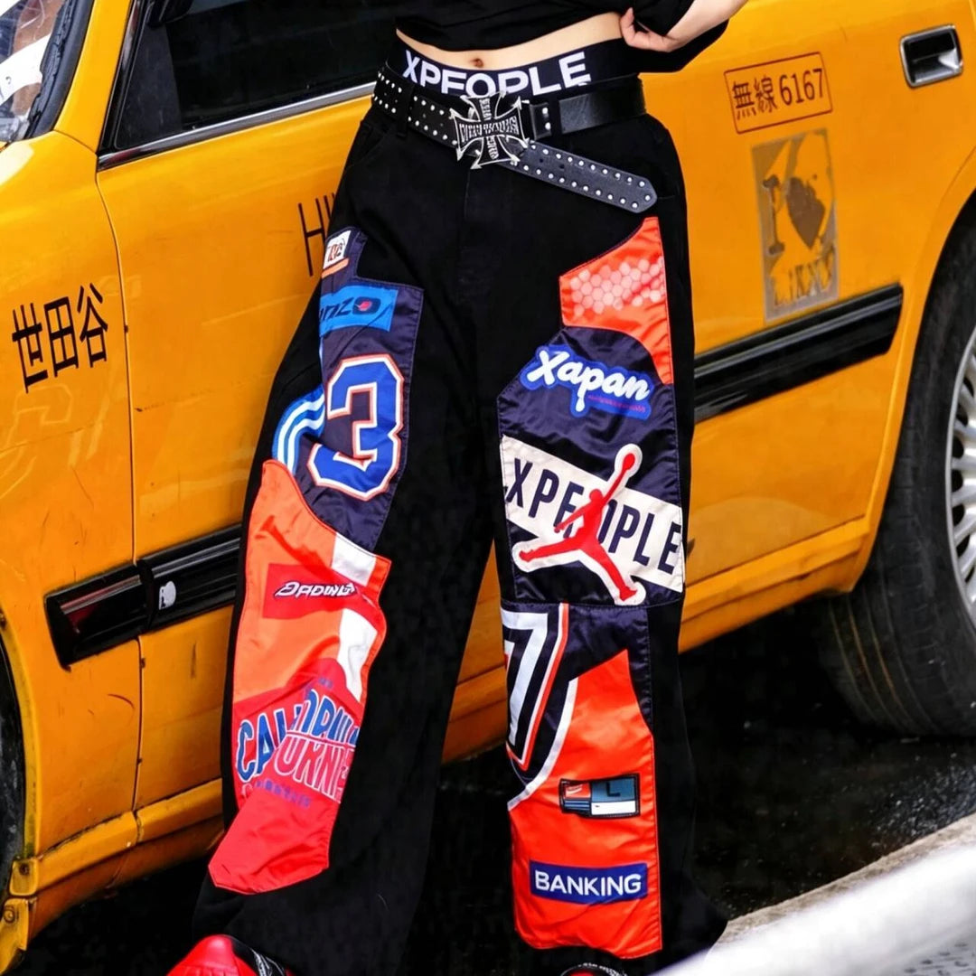 Sanhoostudio denim pants featuring patchwork applique detailing, distressed washed finish, and a wide leg scythe-cut silhouette. Designed for contemporary streetwear styling with relaxed comfort, durable construction, and standout everyday versatility.