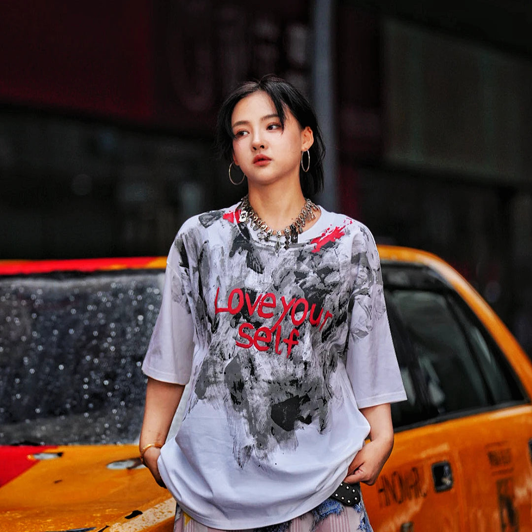 Sanhoostudio short sleeve T-shirt featuring abstract spray-print artwork, breathable fabric construction, and a relaxed oversized fit. Designed for modern streetwear styling with lightweight comfort, bold graphic appeal, and versatile summer wear.