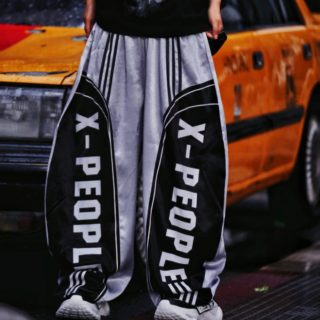 Sanhoostudio wide leg pants featuring a lightweight glossy fabric, relaxed scythe-cut silhouette, and breathable construction for summer comfort. Designed for versatile streetwear styling with a clean modern look and effortless everyday wear.