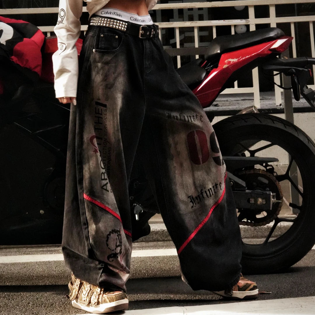 Sanhoostudio denim pants featuring frayed patchwork detailing, distressed wash treatment, and a relaxed scythe-cut silhouette. Designed for modern streetwear styling with a loose straight-leg fit, vintage character, and versatile everyday appeal.