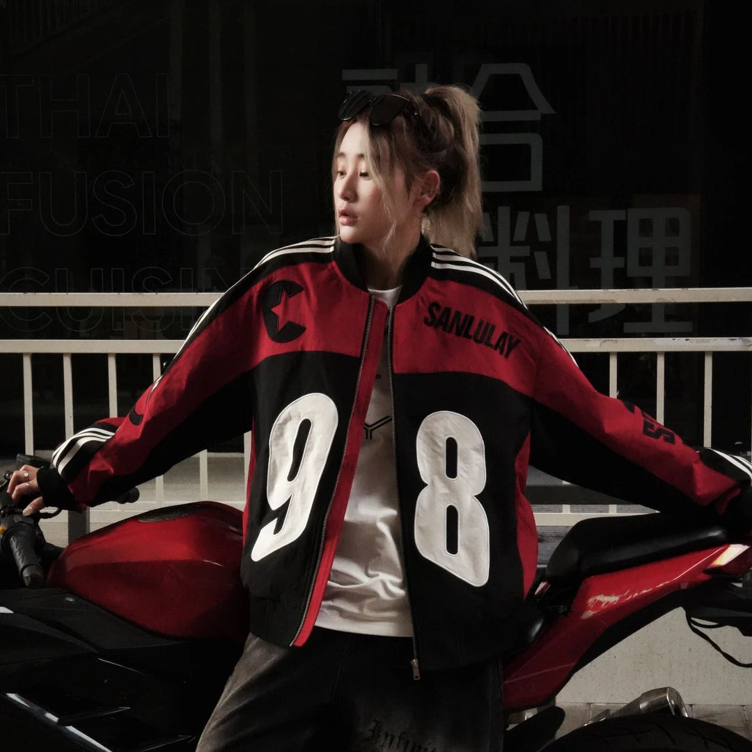 Sanhoostudio bomber jacket featuring black and white colorblock panels, number and letter graphics, a zip-up front, and a cropped racing-inspired silhouette. Designed for early fall streetwear with sporty motorcycle character and versatile everyday layering.