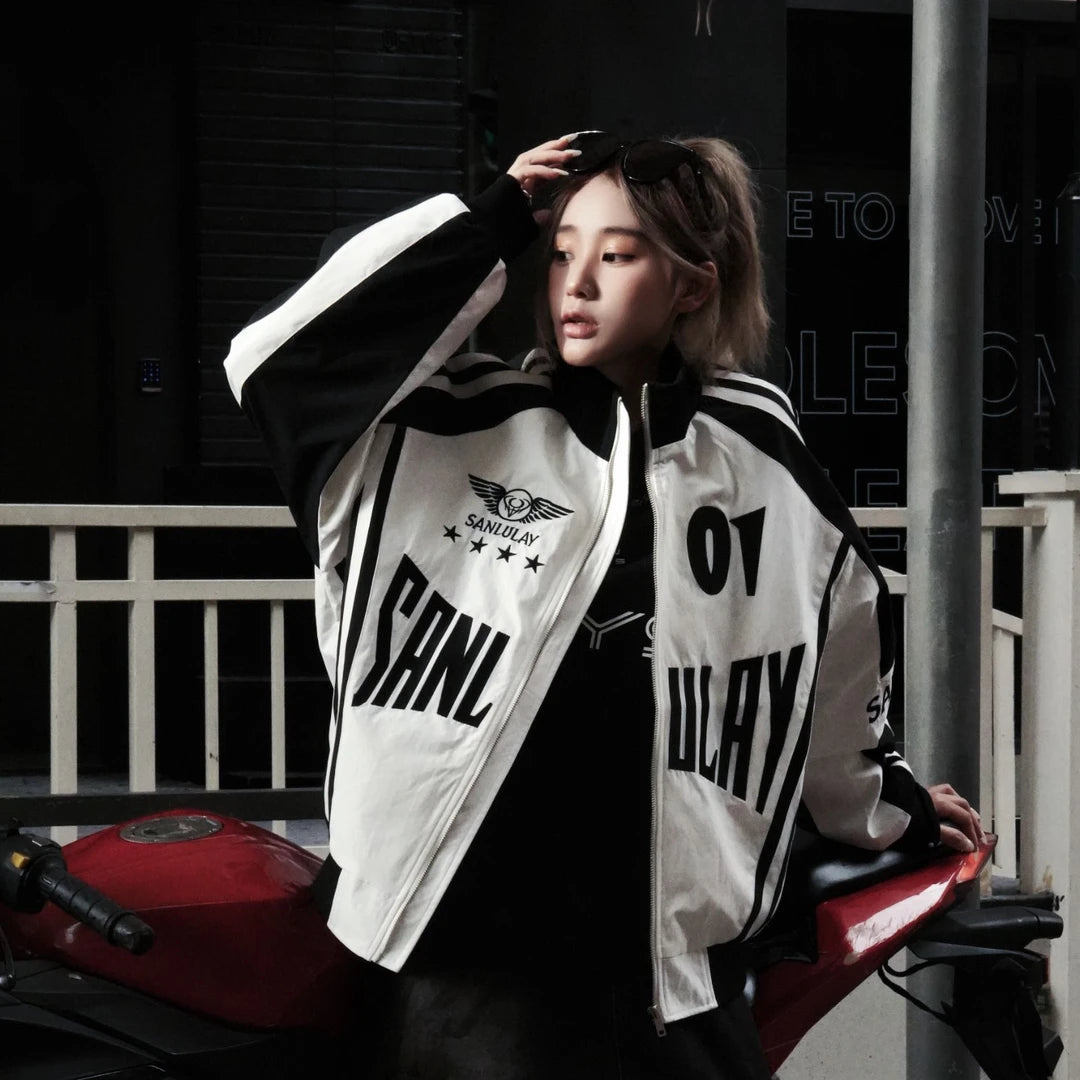 Sanhoostudio varsity jacket featuring red and black colorblock construction, number applique embroidery, striped detailing, and a relaxed oversized fit. Inspired by vintage racing and varsity aesthetics for bold fall streetwear styling and comfortable everyday wear.