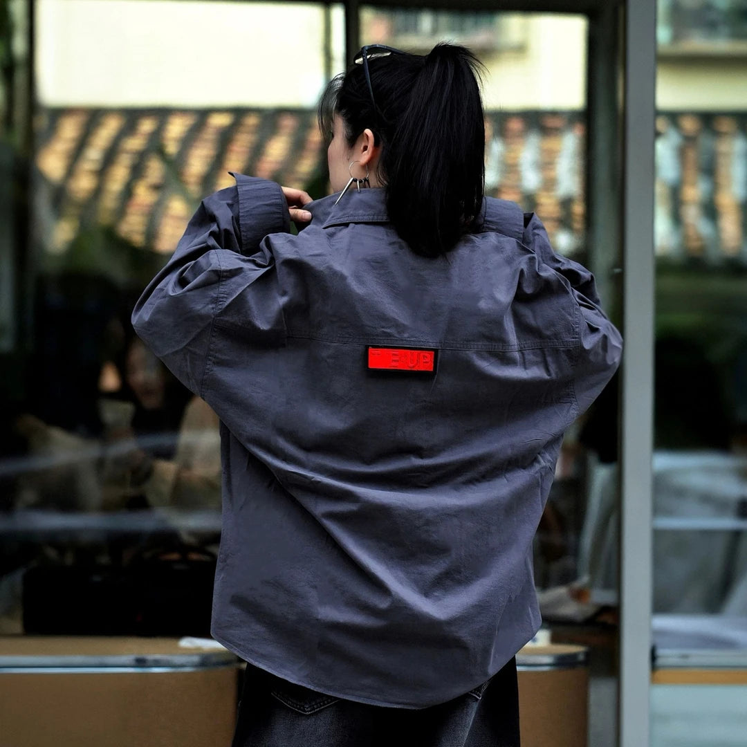 Sanhoostudio long sleeve shirt featuring metallic-effect letter detailing, relaxed dropped shoulders, and an oversized silhouette. Designed for dark high-street styling with bold visual texture, comfortable layering, and a sleek urban aesthetic for versatile everyday outfits.