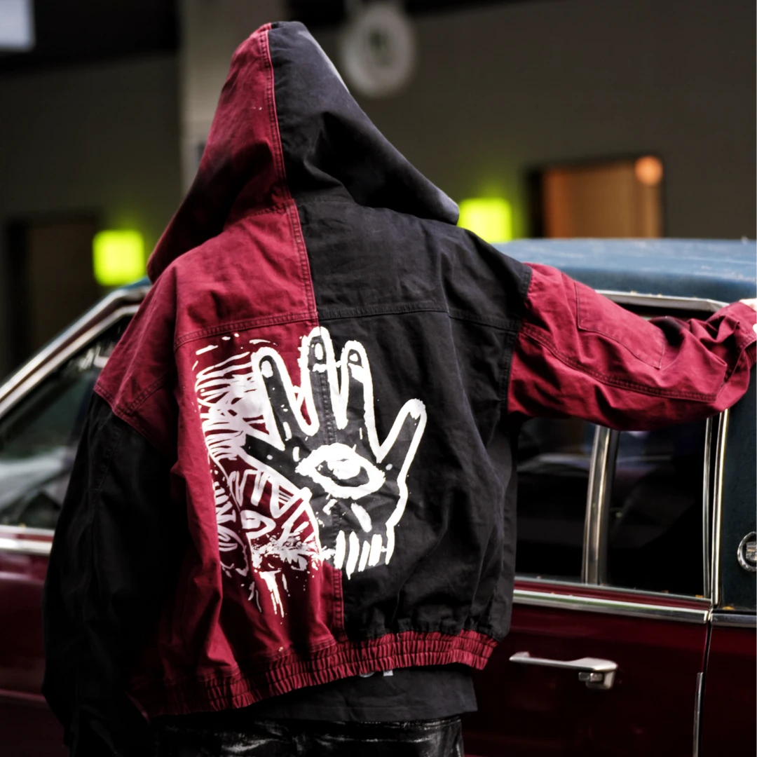Sanhoostudio denim jacket featuring evil-eye inspired applique embroidery, distressed stain effects, and a relaxed oversized silhouette. Designed for statement streetwear layering with handcrafted visual details, rugged vintage texture, and distinctive dark urban character.