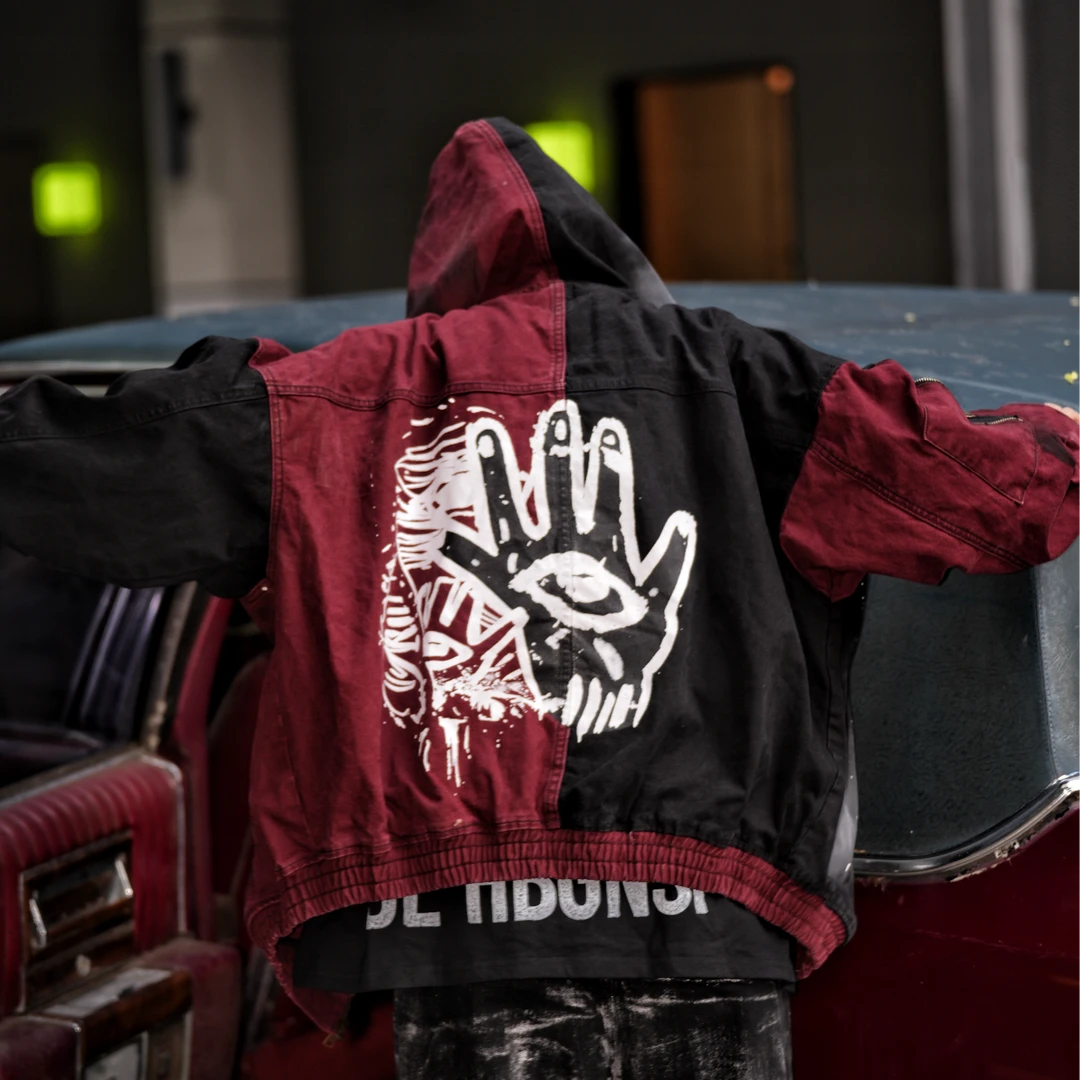 Sanhoostudio denim jacket featuring evil-eye inspired applique embroidery, distressed stain effects, and a relaxed oversized silhouette. Designed for statement streetwear layering with handcrafted visual details, rugged vintage texture, and distinctive dark urban character.