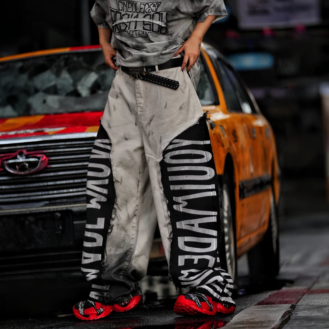 Sanhoostudio denim pants featuring asymmetric panel construction, distressed washed detailing, and a relaxed wide leg scythe silhouette. Designed for lightweight seasonal streetwear styling with distinctive patchwork structure, comfortable movement, and bold contemporary urban appeal.