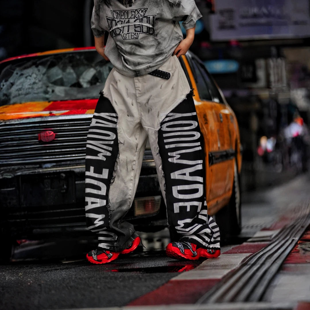 Sanhoostudio denim pants featuring asymmetric panel construction, distressed washed detailing, and a relaxed wide leg scythe silhouette. Designed for lightweight seasonal streetwear styling with distinctive patchwork structure, comfortable movement, and bold contemporary urban appeal.