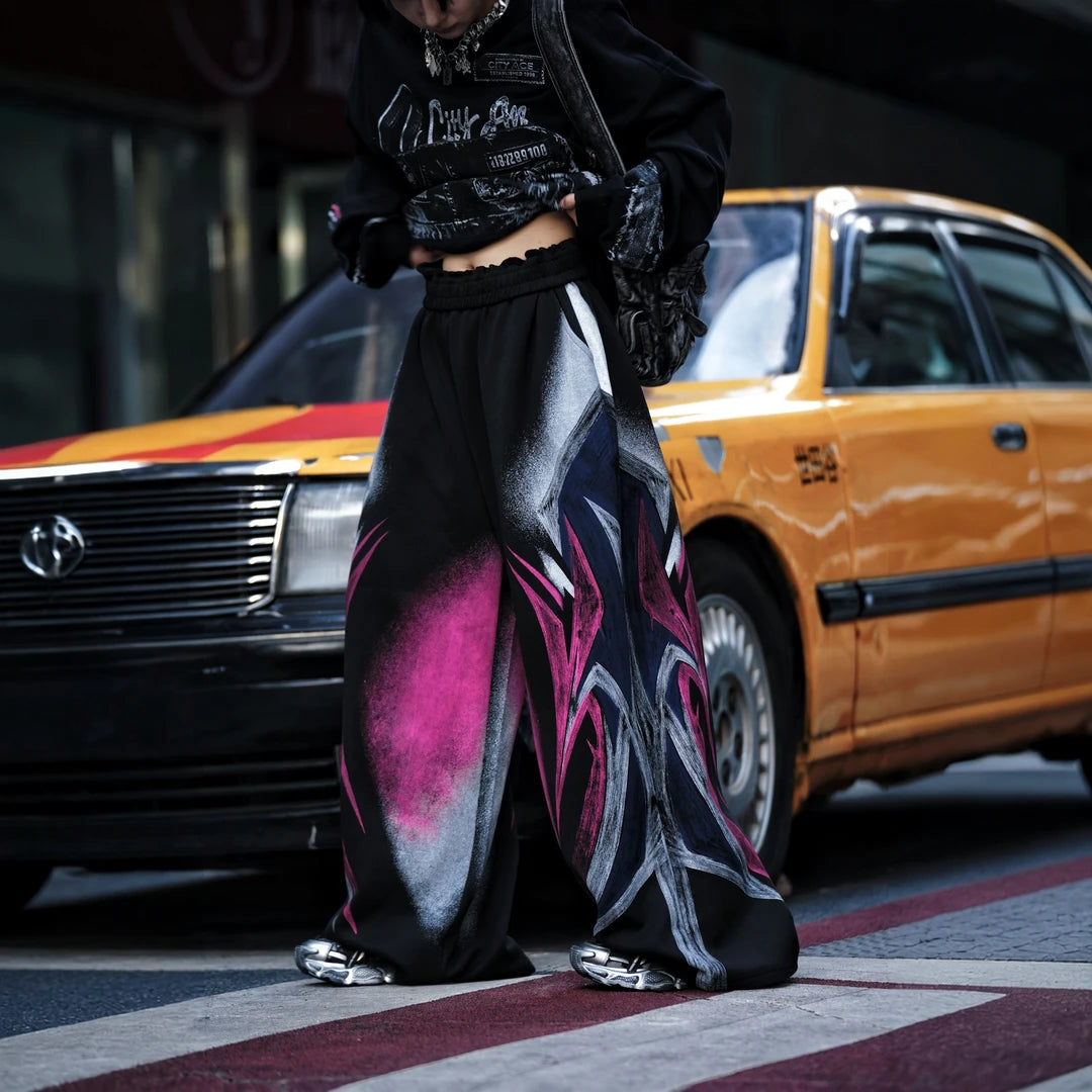 Sanhoostudio sweatpants featuring colorful washed treatment, distressed detailing, patchwork construction, and a relaxed wide leg scythe silhouette. Designed for statement streetwear styling with heavyweight texture, comfortable movement, oversized proportions, and distinctive everyday appeal.
