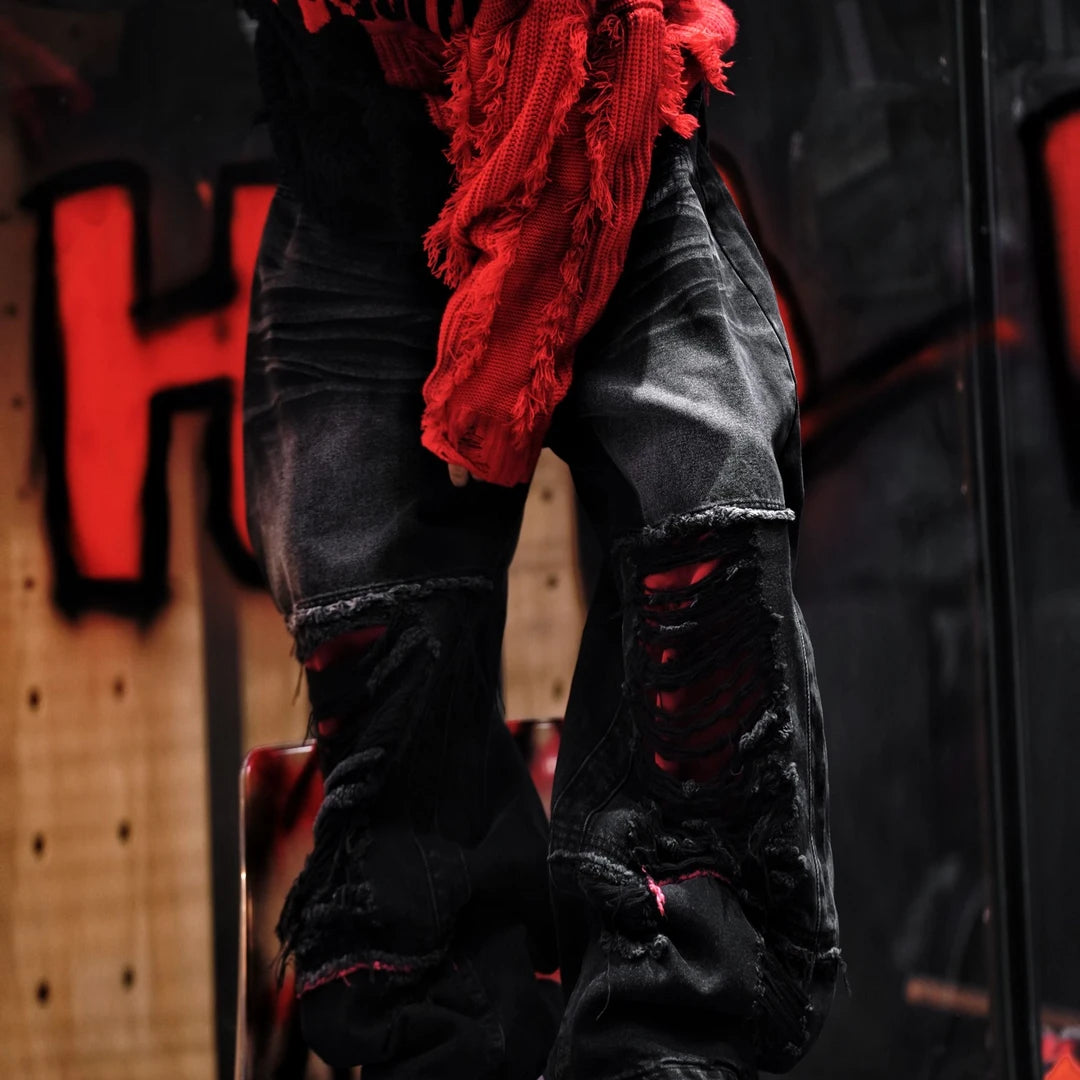 Sanhoostudio denim pants featuring a bold red colorway, heavyweight washed denim, distressed detailing, and patchwork construction with a wide leg scythe silhouette. Designed for statement streetwear styling with rugged texture, relaxed proportions, and distinctive visual appeal.