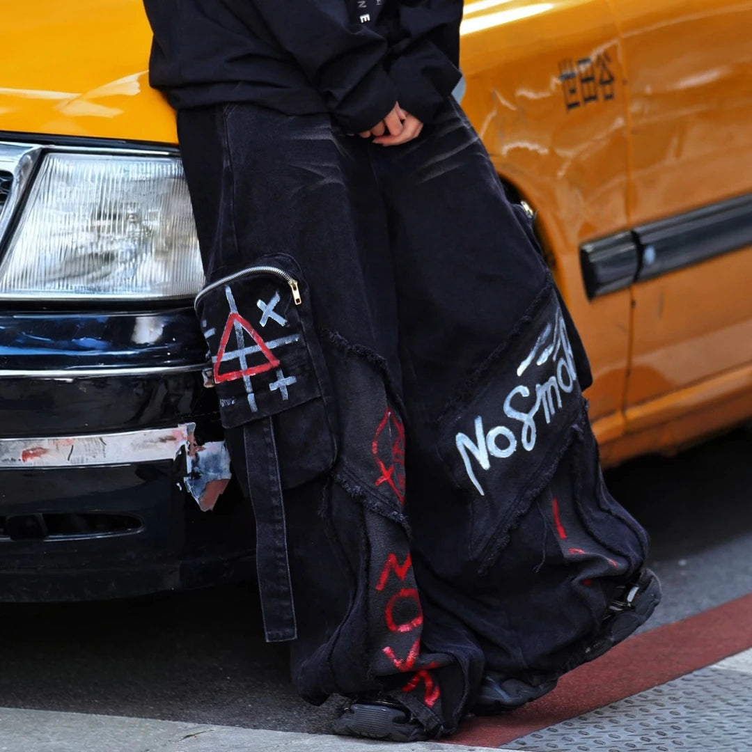 Sanhoostudio cargo denim pants featuring bold graffiti artwork, vintage washed treatment, distressed detailing, and a relaxed wide leg silhouette. Designed for American-inspired streetwear styling with rugged denim texture, functional workwear character, oversized proportions, and versatile everyday appeal.