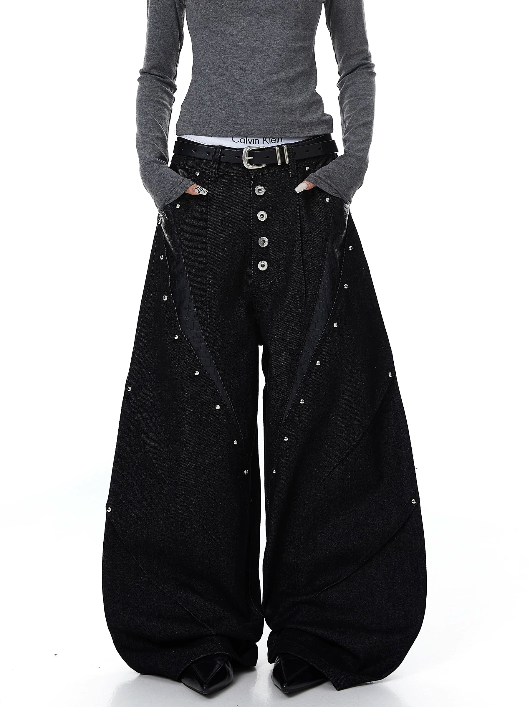 Sanhoostudio denim pants featuring leather patchwork, studded details, and button accents. Designed with a wide leg silhouette for bold streetwear looks.