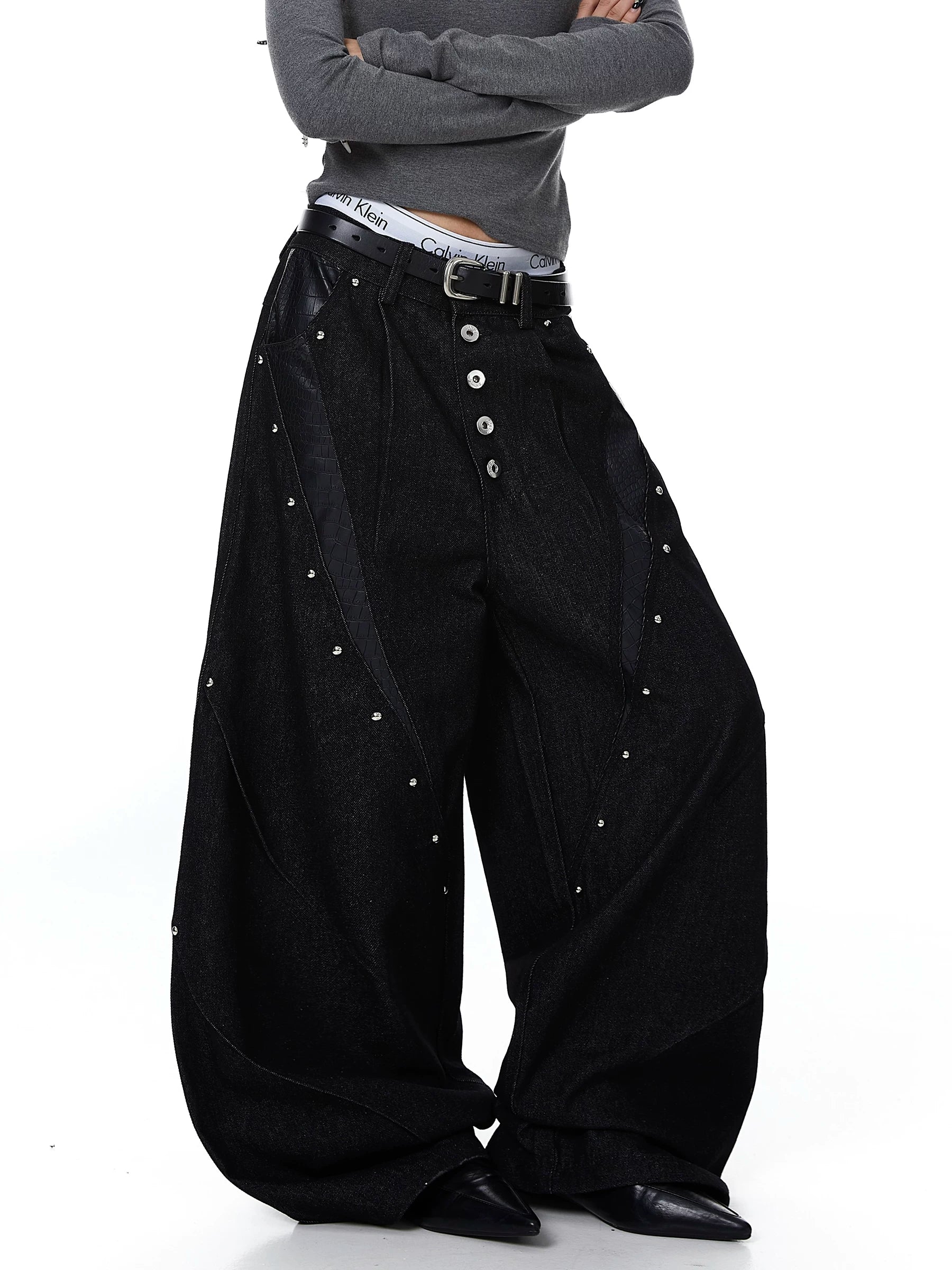 Sanhoostudio denim pants featuring leather patchwork, studded details, and button accents. Designed with a wide leg silhouette for bold streetwear looks.