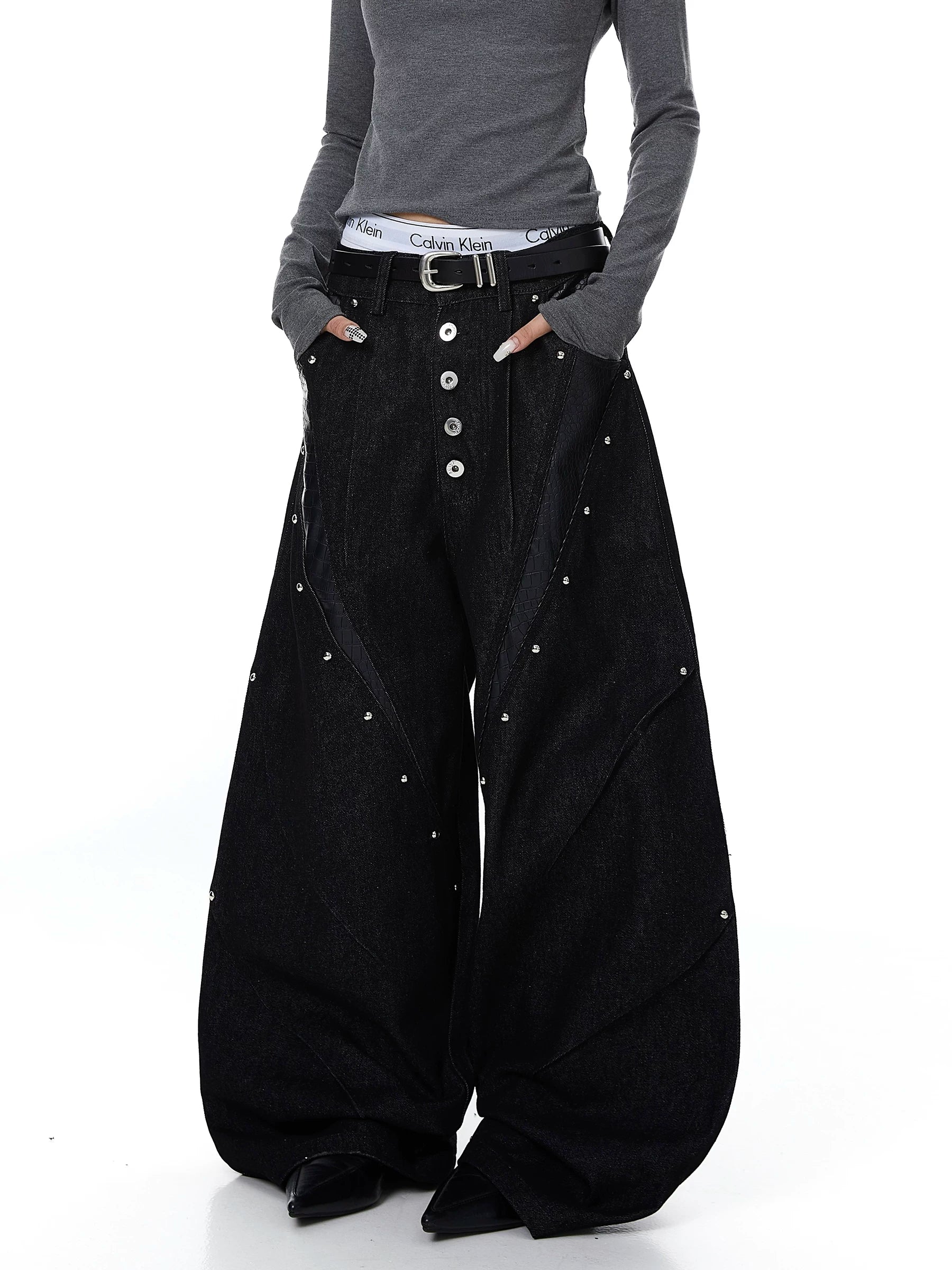 Sanhoostudio denim pants featuring leather patchwork, studded details, and button accents. Designed with a wide leg silhouette for bold streetwear looks.