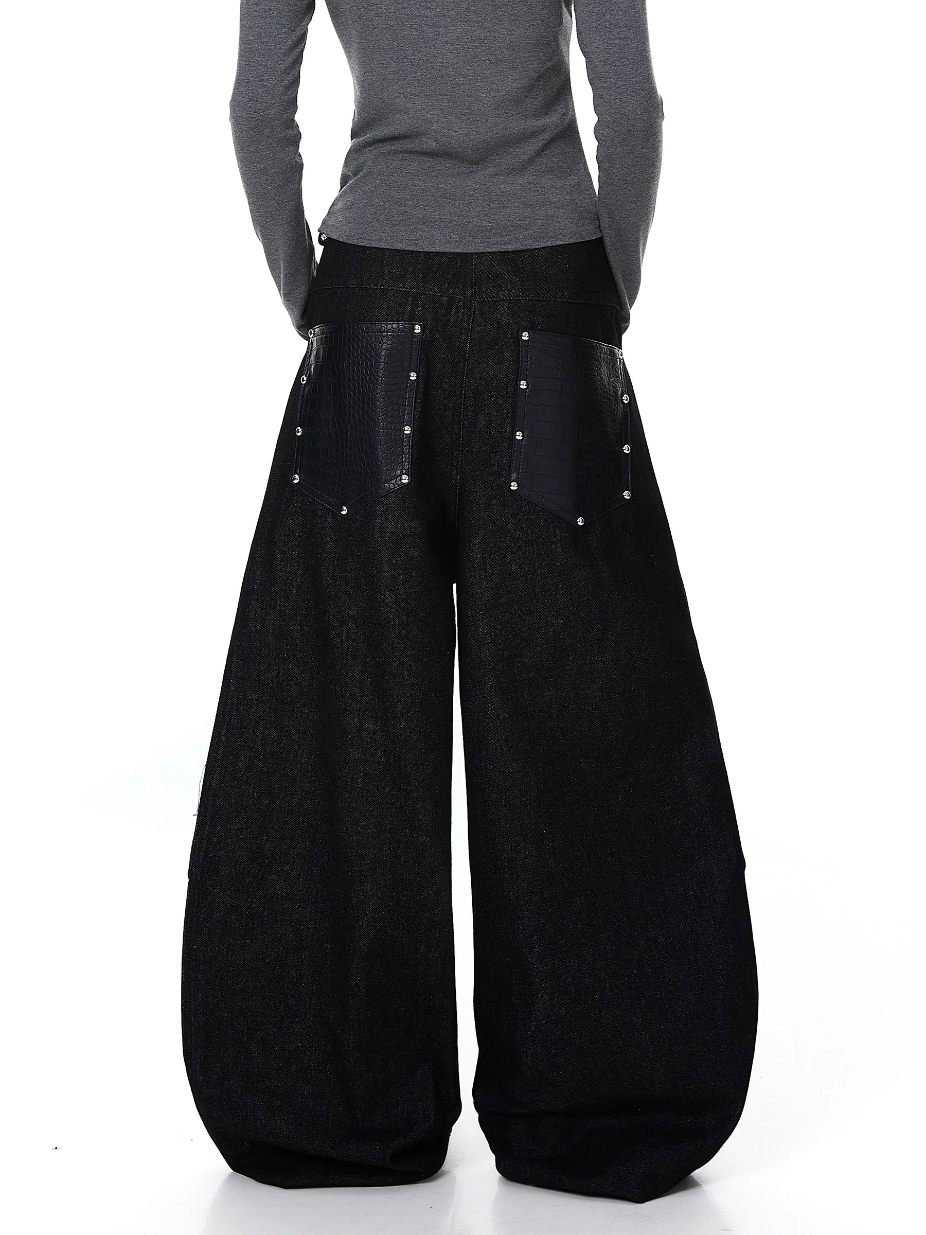 Sanhoostudio denim pants featuring leather patchwork, studded details, and button accents. Designed with a wide leg silhouette for bold streetwear looks.
