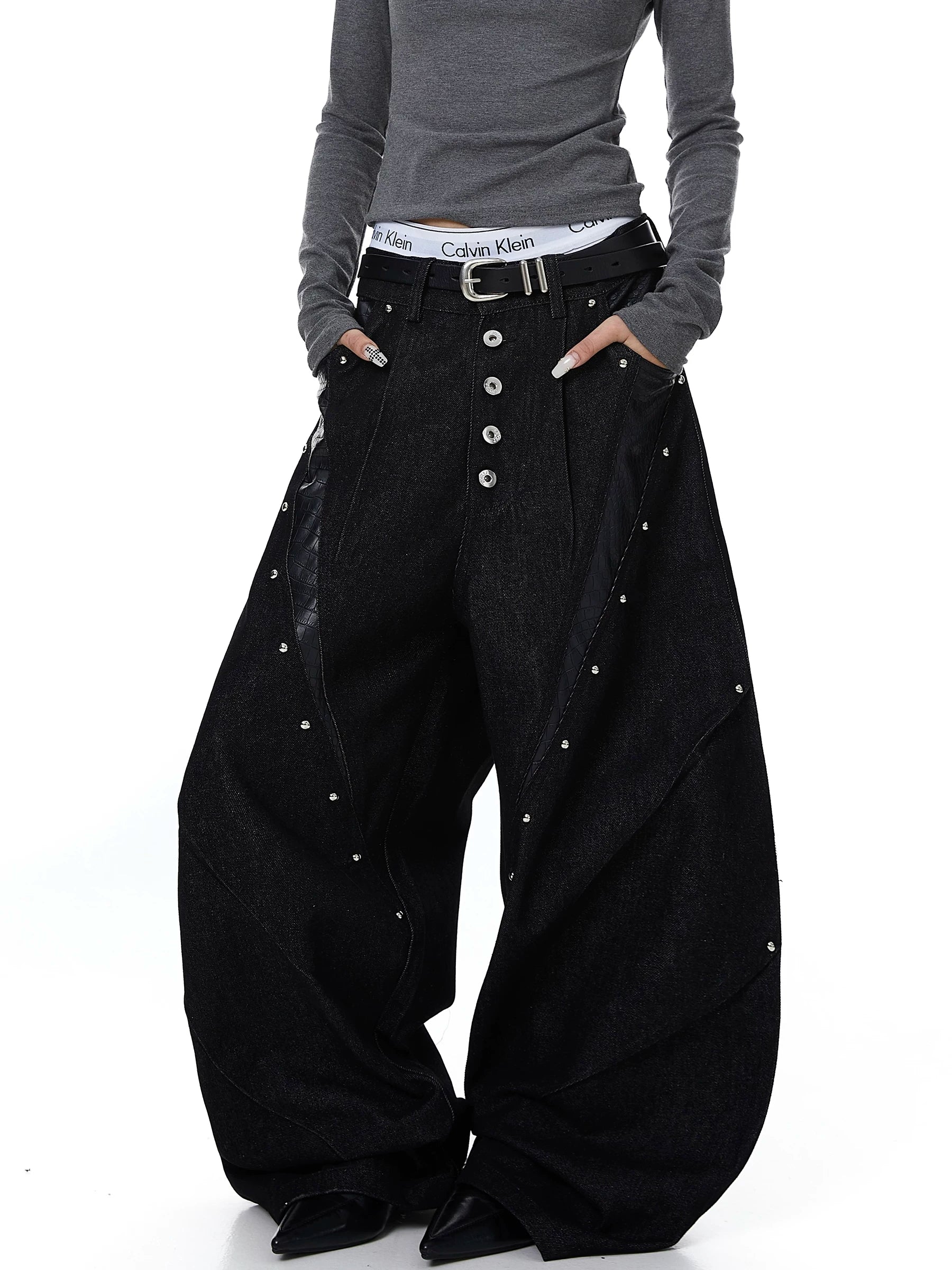 Sanhoostudio denim pants featuring leather patchwork, studded details, and button accents. Designed with a wide leg silhouette for bold streetwear looks.