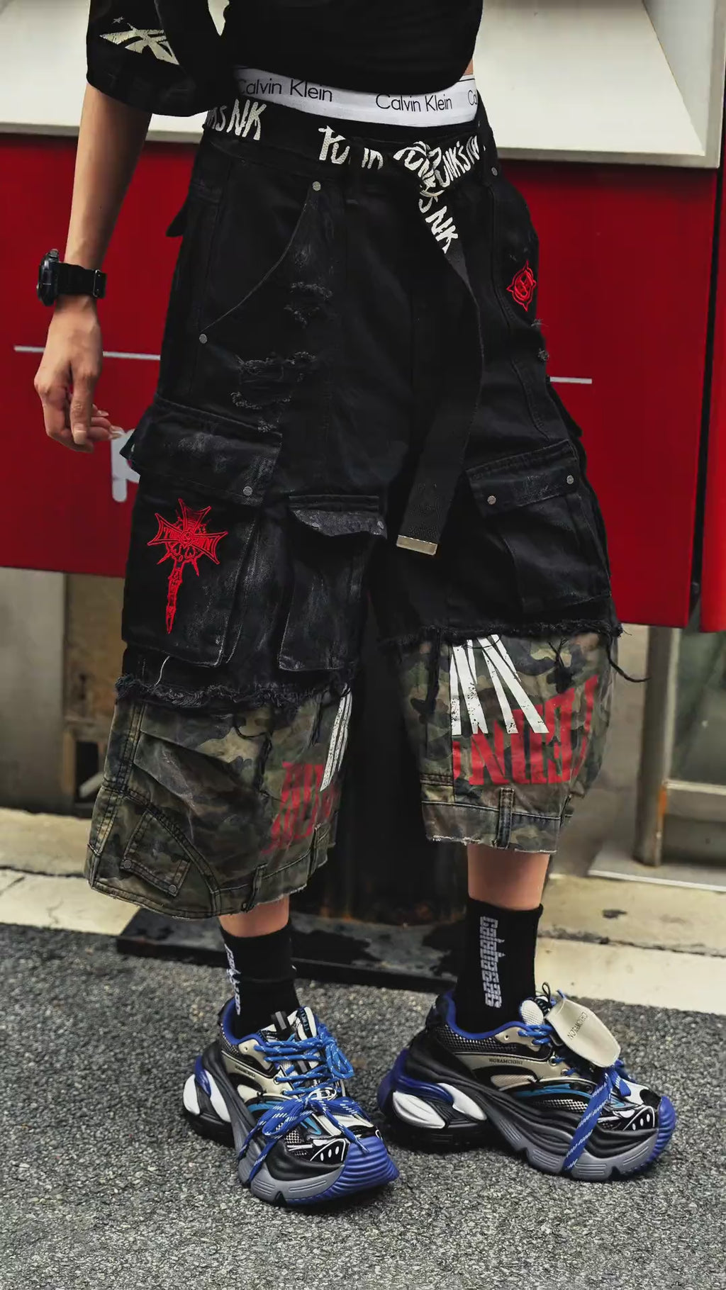 Sanhoostudio denim cargo shorts featuring camouflage patchwork design, multi-pocket construction, and wide leg silhouette. Perfect for summer streetwear styling with breathable comfort, functionality, and versatile daily wear.